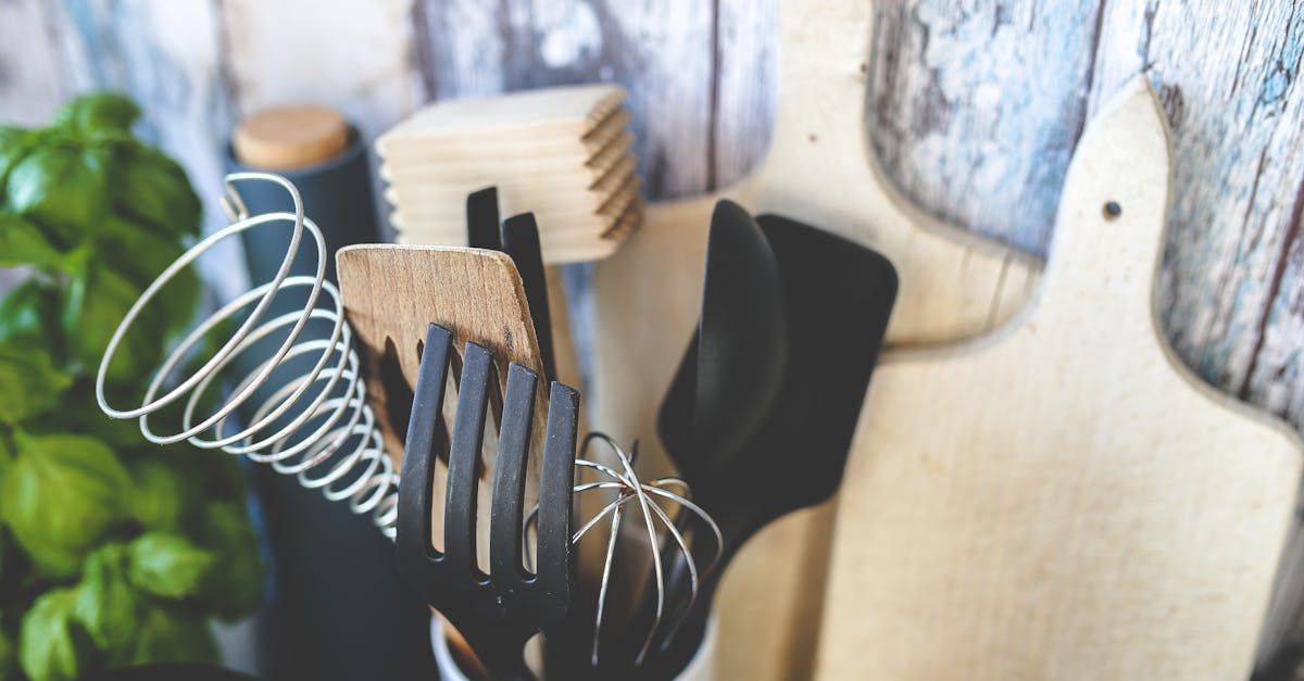 Collection of kitchen utensils including spatula, whisk, and chopping boards against a rustic background.