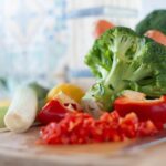 Colorful vegetables including broccoli and bell peppers on a chopping board, perfect for healthy cooking concepts.