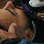 A barber skillfully shapes a beard with clippers, showcasing precision in men's grooming.