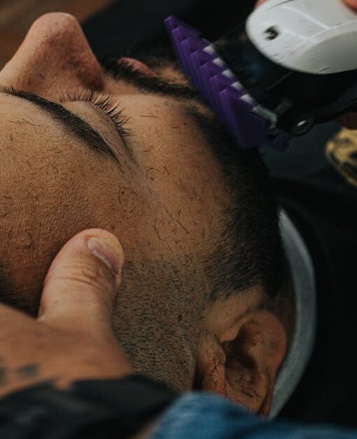A barber skillfully shapes a beard with clippers, showcasing precision in men's grooming.