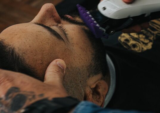 A barber skillfully shapes a beard with clippers, showcasing precision in men's grooming.