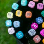Top view of colorful art markers in a bag placed on grass, showcasing creativity outdoors.
