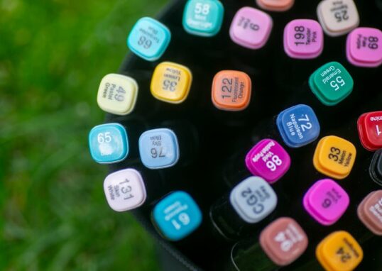 Top view of colorful art markers in a bag placed on grass, showcasing creativity outdoors.
