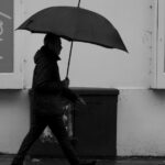 A person walks with a black umbrella on a rainy day in Cheltenham, England.