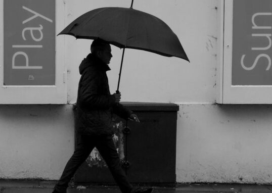 A person walks with a black umbrella on a rainy day in Cheltenham, England.
