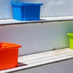 Brightly colored plastic storage boxes on outdoor steps in sunlight.