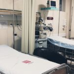 An empty hospital room equipped with two beds, monitoring equipment, and ambient lighting.