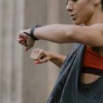 Woman in activewear checking her fitness tracker in an outdoor urban setting.