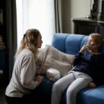 A mother assists her sick child using a nebulizer at home, providing comfort and care.
