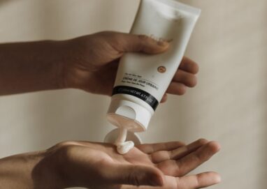 Close-up of a woman squeezing lotion onto her hand, emphasizing skincare and self-care routine.
