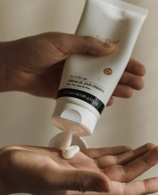 Close-up of a woman squeezing lotion onto her hand, emphasizing skincare and self-care routine.