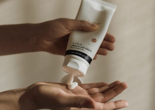 Close-up of a woman squeezing lotion onto her hand, emphasizing skincare and self-care routine.