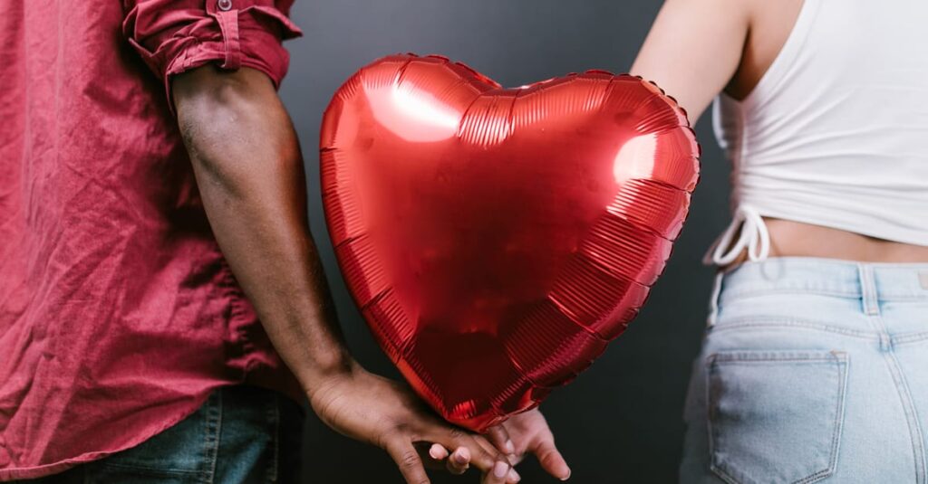 A couple holding a red heart-shaped balloon, symbolizing love and romance for Valentine's Day.