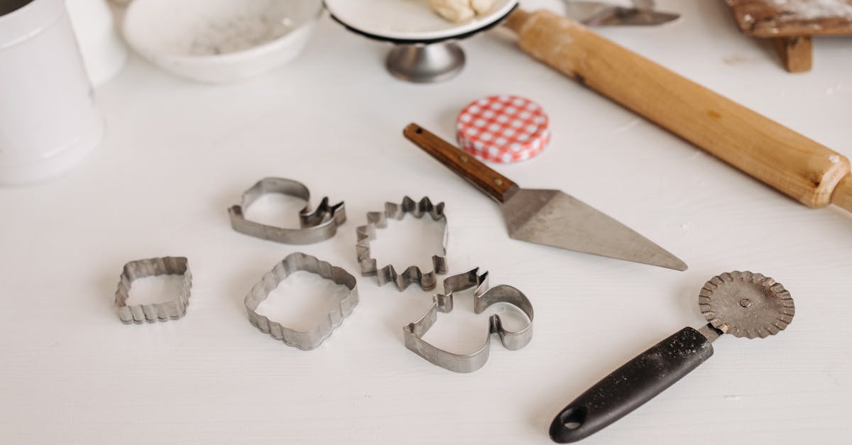 Selection of baking tools with cookie cutters and dough on a white surface, perfect for creative baking.