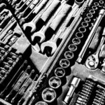 Close-up black and white photo of a complete wrench and socket tool set within a toolbox.
