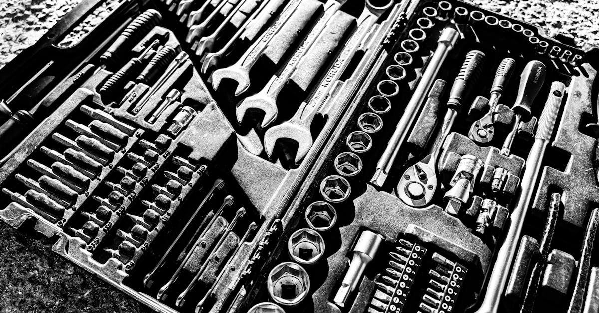 Close-up black and white photo of a complete wrench and socket tool set within a toolbox.
