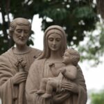 Sculpture of Saint Joseph, Virgin Mary, and Jesus outdoors.