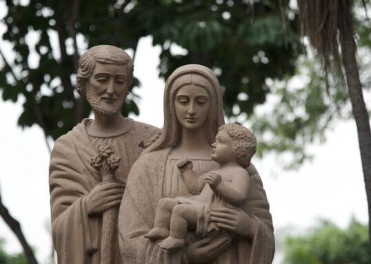 Sculpture of Saint Joseph, Virgin Mary, and Jesus outdoors.
