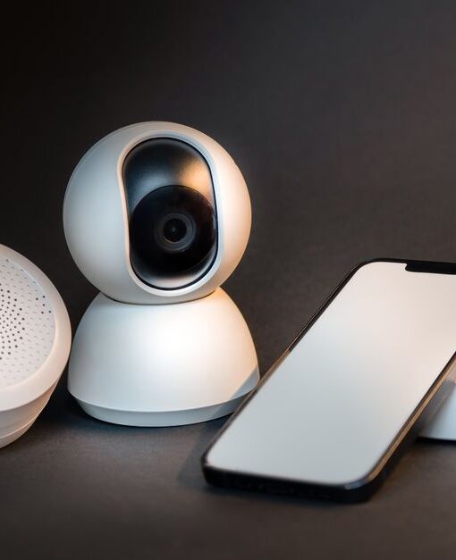 A sleek smartphone with modern smart home devices on a minimalist gray background.