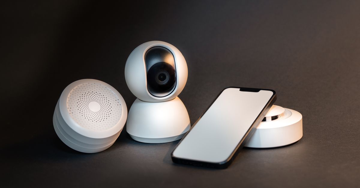 A sleek smartphone with modern smart home devices on a minimalist gray background.