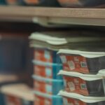 Rows of neatly stacked food containers in various colors on store shelves.