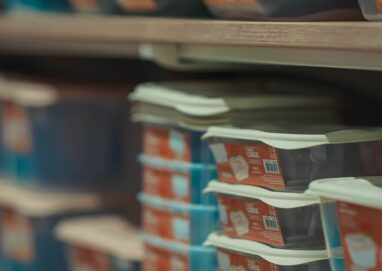 Rows of neatly stacked food containers in various colors on store shelves.