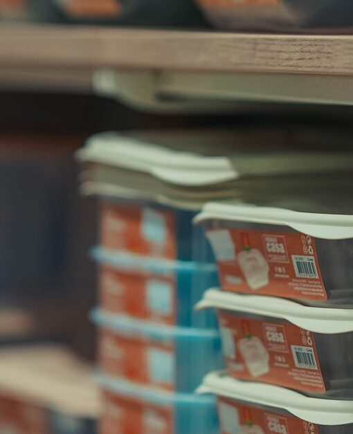 Rows of neatly stacked food containers in various colors on store shelves.
