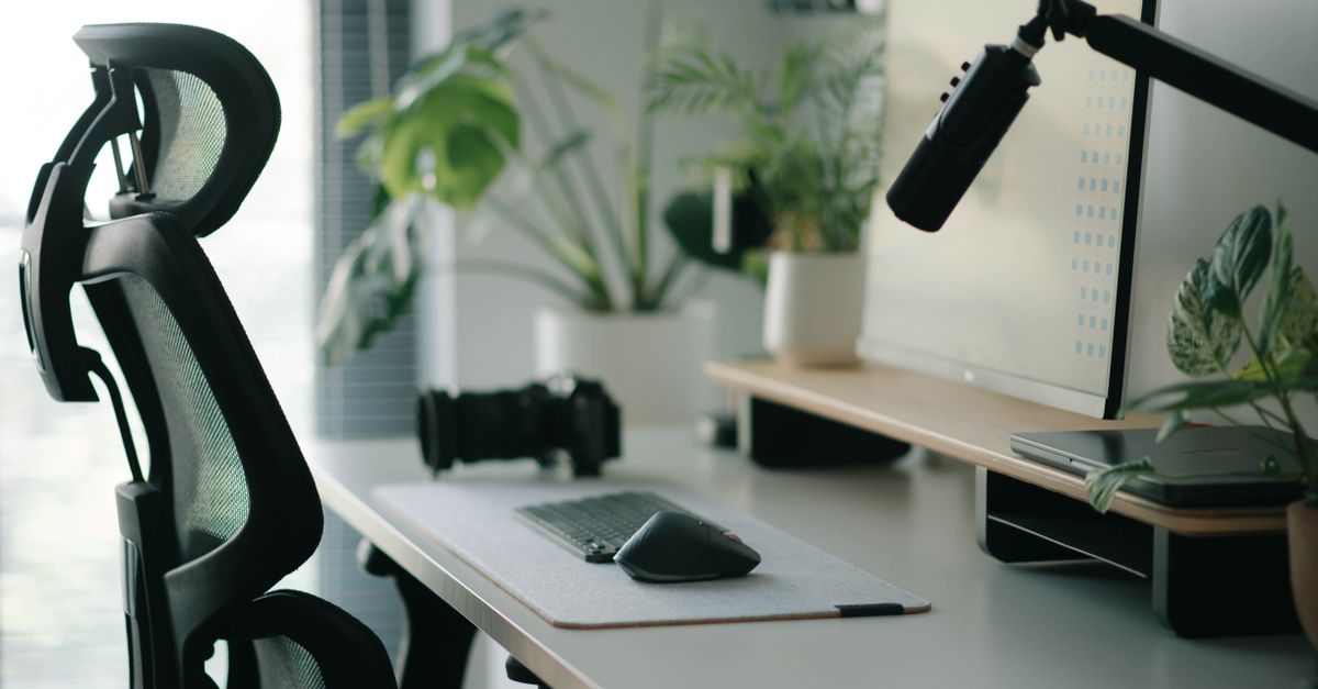 Stylish home office setup with ergonomic chair, plants, and tech accessories creating a modern work environment.