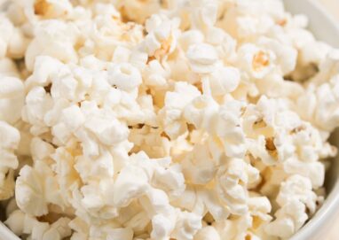 Close-up of freshly popped popcorn in a white bowl, perfect for a movie night snack.